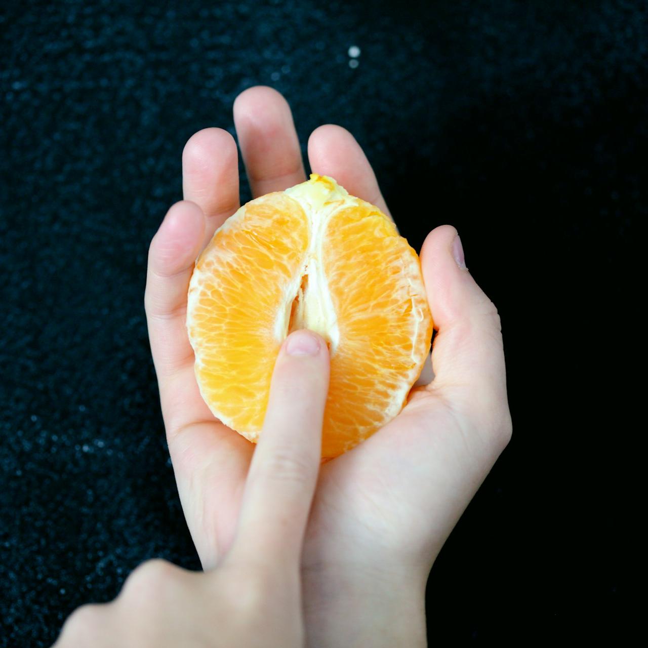 person holding sliced orange fruit