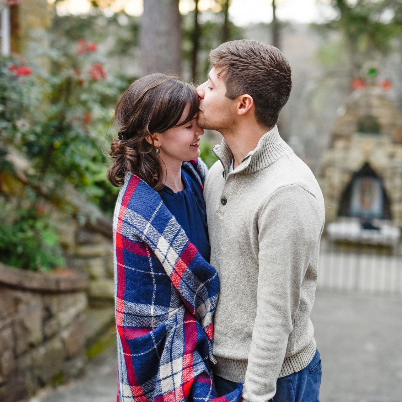 man kissing on woman forehead standing near tree during daytime man kissing on woman forehead standing near tree during daytime